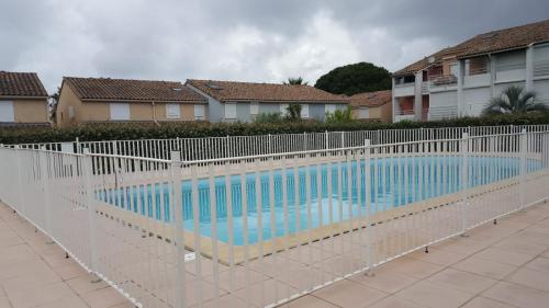 une piscine entourée d'une clôture blanche. dans l'établissement villa les bastides de l olivier grau du roi, au Grau-du-Roi