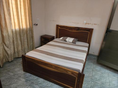 a bed in a bedroom with a wooden headboard at Appartements meublés village CAN in Bamako