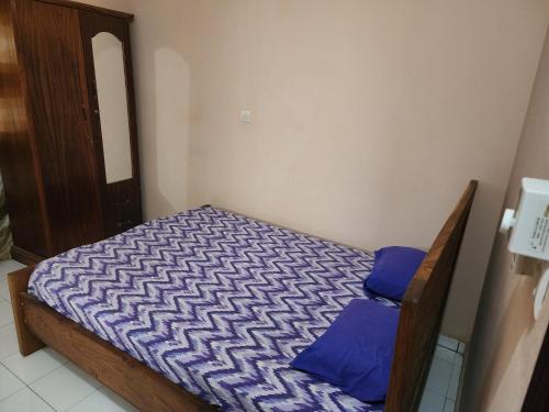 a small bed with blue pillows in a room at Appartements meublés village CAN in Bamako