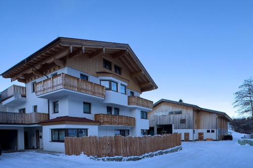 an apartment building with a wooden fence in the snow at Ferienwohnung am Bauernhof, Korbingerhof in Rinn