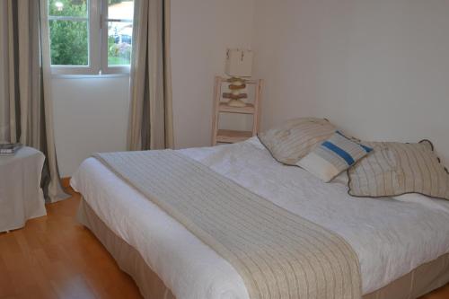 una cama blanca con almohadas y una ventana en una habitación en Villa avec Piscine chauffée et parc arboré située à 100 m de la Plage et Forêt sans vis à vis, en Saint-Trojan-les-Bains