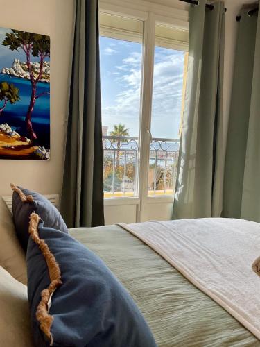 a bedroom with a bed and a large window at App'ART GALERIE Vue mer in Sausset-les-Pins