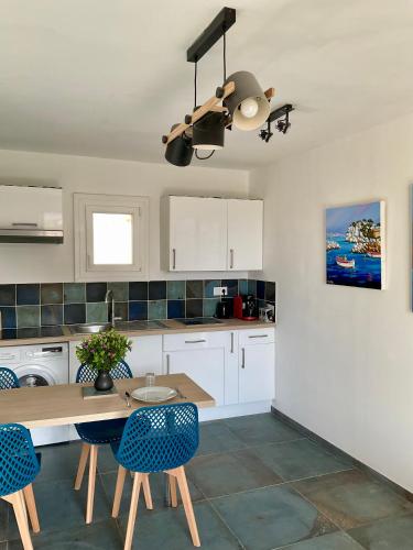 a kitchen with white cabinets and a table and chairs at App'ART GALERIE Vue mer in Sausset-les-Pins