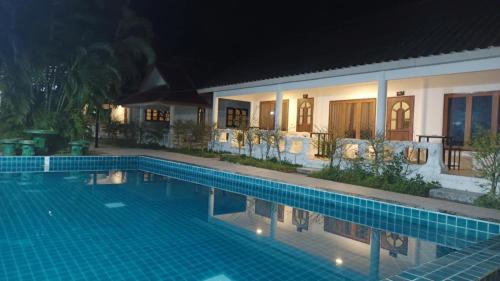 a swimming pool in front of a house at night at Pai Family Resort in Pai