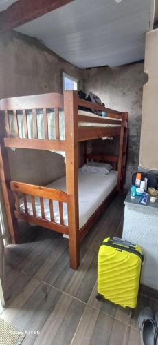 a room with two bunk beds and a yellow suitcase at VAL's Hostel in Guarujá