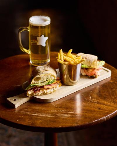 a sandwich and french fries on a table with a glass of beer at The Harcourt Arms in Witney