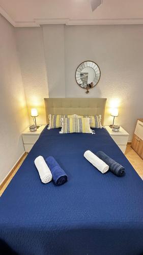 Una gran cama azul con 3 almohadas. en Apartament MARA, en Torrevieja