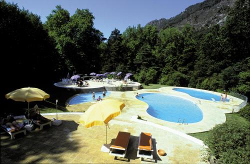 un paio di piscine con ombrelloni e persone sedute intorno di Águas do Gerês - Hotel, Termas & Spa a Geres