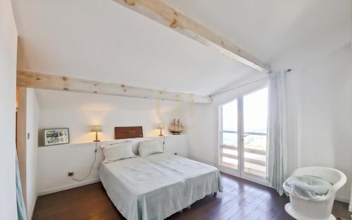 une chambre blanche avec un lit et une grande fenêtre dans l'établissement Superbe T5 centre-ville vue mer, à LʼÎle-Rousse