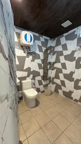 a bathroom with a toilet and a wall with tiles at Hotel Maheshwari & Banquet Hall in Tehri-Garhwāl