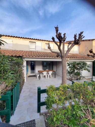une maison avec un patio et un arbre dans l'établissement villa les bastides de l olivier grau du roi, au Grau-du-Roi