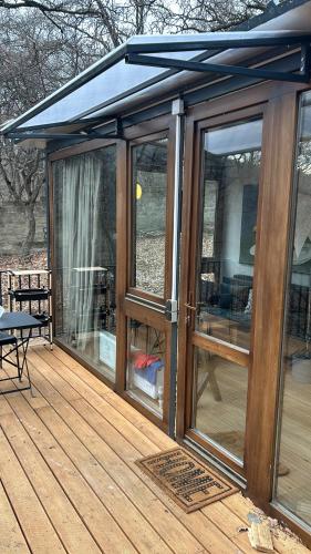 a wooden deck with sliding glass doors on it at Nina's winery forest house in Kiketi in Tbilisi City