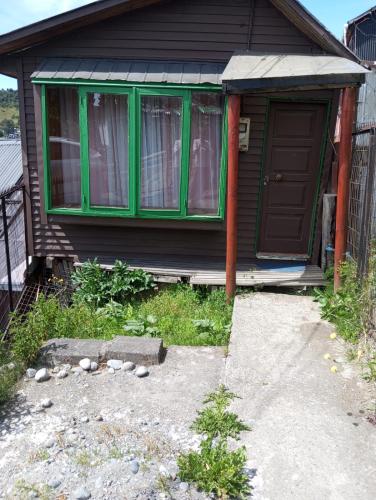 ein Haus mit grünen Fenstern und einer Tür in der Unterkunft Cabaña Punta Diamante in Castro