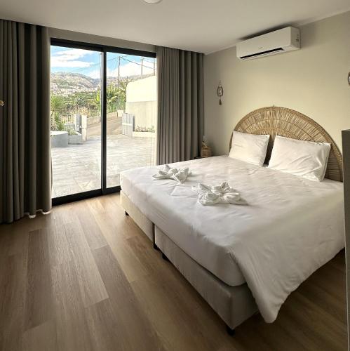 a bedroom with a large white bed with a large window at Oásis Suites - Funchal in Funchal