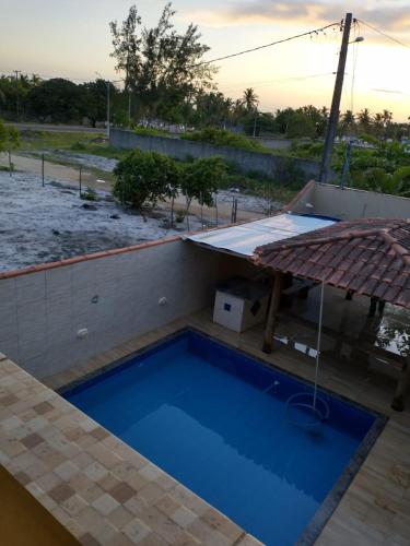 a blue swimming pool next to a building with a roof at Recanto Rocha in Nova Viçosa