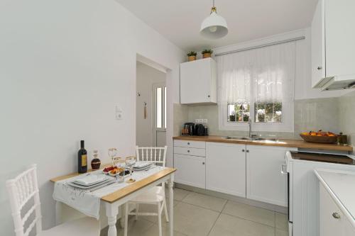 a kitchen with white cabinets and a wooden table at Relaxing House with Garden in Nea Makri