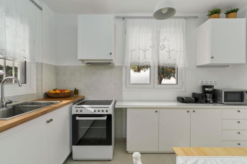 a white kitchen with a sink and a stove at Relaxing House with Garden in Nea Makri