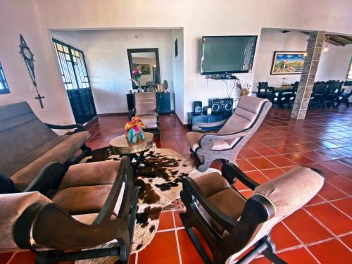 a living room with a couch and chairs and a tv at Casa Campestre Las Julianas in Socorro