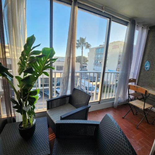 un salon avec un canapé et des chaises et une grande fenêtre dans l'établissement Appartement à deux pas de la mer, à Saint-Laurent-du-Var
