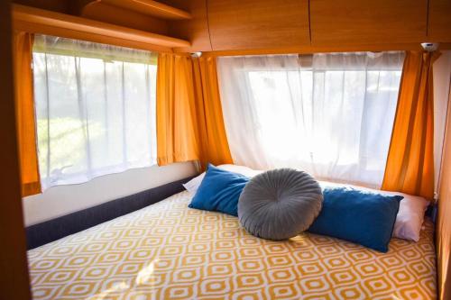 a bedroom with a bed with blue pillows and a window at Caravan near the sea 4 in Ugljan