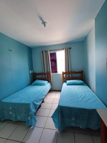 two beds in a room with blue walls and a window at Apartamento Mobiliado Vila Iracema in Fortaleza