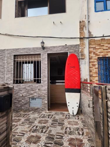 a red and white surfboard leaning against a building at Tafedna Beach House in Essaouira