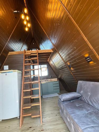 a room with a ladder and a couch in a attic at Cabana Aroma do Mar in Jaguaruna