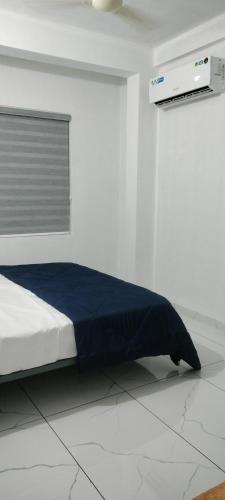 a white room with a bed with a blue blanket at Little home apartment in Kozhikode