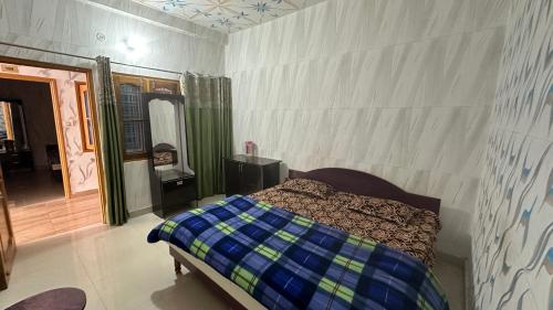 a bedroom with a bed with a blue and green comforter at Hotel Maheshwari & Banquet Hall in Tehri-Garhwāl
