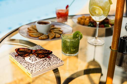 a glass table with a plate of food and a glasses at Royal Golden Hotel - Savassi in Belo Horizonte