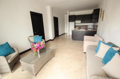 a living room with couches and a table with flowers at Ocean Blue Hotel in Olón