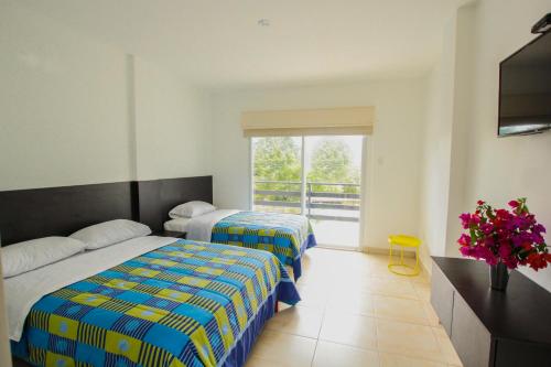 a hotel room with two beds and a window at Ocean Blue Hotel in Olón