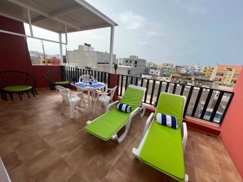 a balcony with green chairs and a table with a view at FRANMAY APARTMENTS - 7 modern apartments near the beach & city in Santa Maria