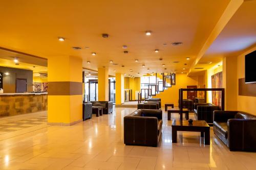 a lobby with couches and tables and yellow walls at Hotel Maxim in Arad