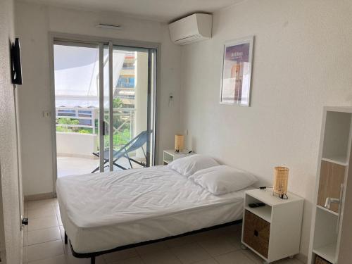 une chambre blanche avec un lit et un balcon dans l'établissement F2 totalement rénové, 200 m de la plage, piscine, parking, tout à pieds, à Antibes