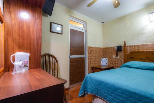 a bedroom with a bed and a wooden desk and a table at Hotel el Carmen, Morelia in Morelia