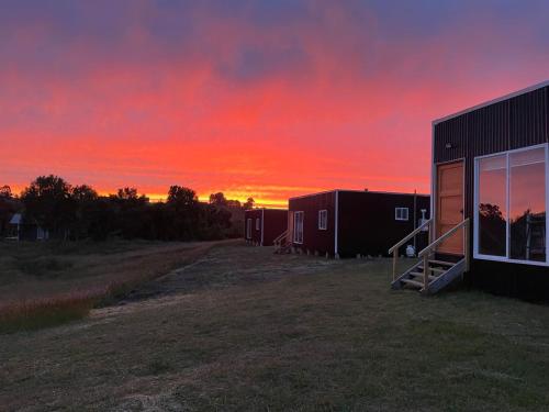a building with a sunset in the background at Quilquico Lodge in Castro