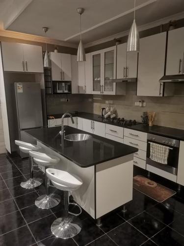 una cucina con mobili bianchi, un lavandino e sgabelli di Tina's Place a Lilongwe