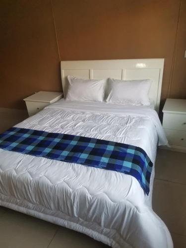 un letto con una coperta blu e bianca sopra di Tina's Place a Lilongwe