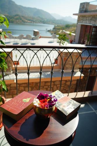 a table with a bowl of flowers and books on a balcony at Saket LOAK in Udaipur