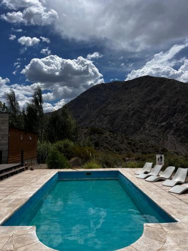 a swimming pool with chairs and mountains in the background at Viví Potrerillos in Potrerillos