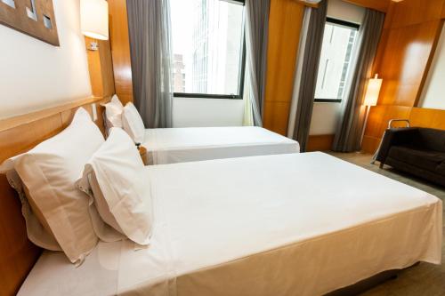 a hotel room with two beds and a window at Royal Golden Hotel - Savassi in Belo Horizonte