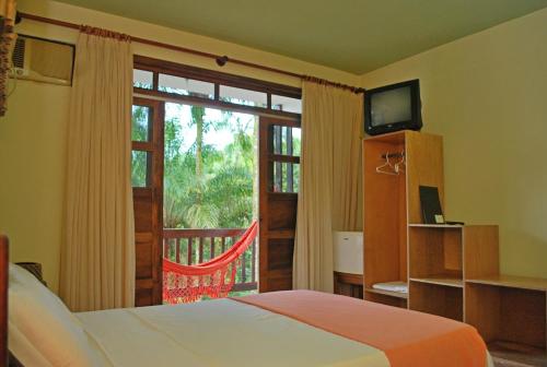 a bedroom with a bed and a window with a balcony at Paraíso das Águas Hotel Bahia in Ituberá