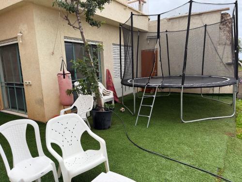 a patio with a trampoline and chairs on the grass at Neve ziv in Neve Ziv
