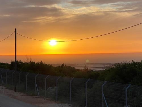a sunset on a hill with a fence at Neve ziv in Neve Ziv