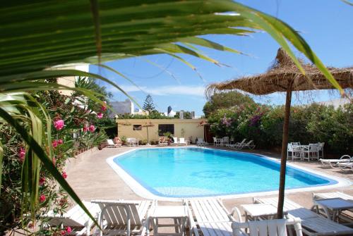 a swimming pool with chairs and an umbrella at Riad Zahra in Essaouira