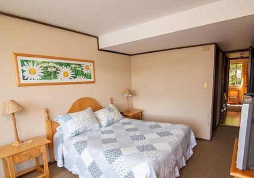 - une chambre avec un lit doté d'une couverture en damier bleu et blanc dans l'établissement Espectacular vista al lago y al volcán, à Pucón
