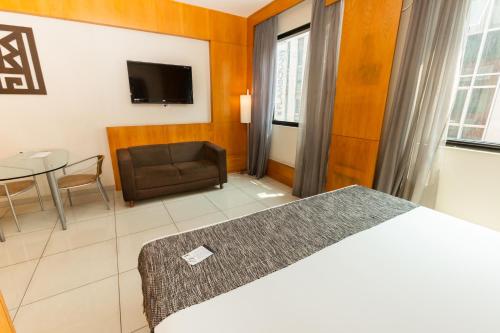 a bedroom with a bed and a couch and a table at Royal Golden Hotel - Savassi in Belo Horizonte