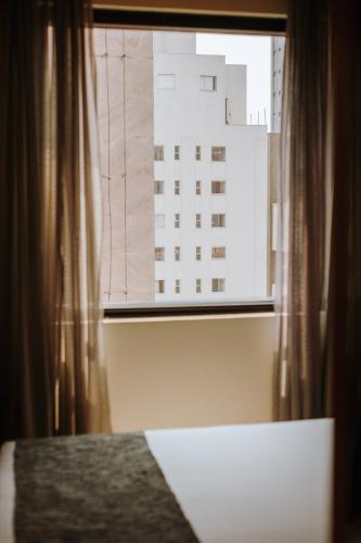 a bedroom window with a view of a building at Royal Golden Hotel - Savassi in Belo Horizonte