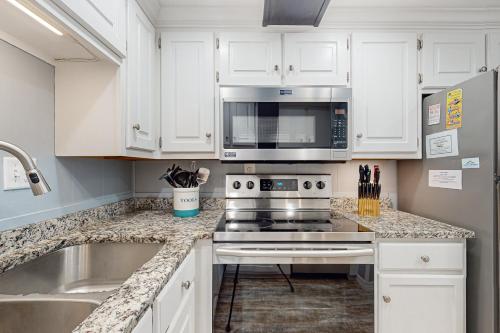 a kitchen with white cabinets and a stove and a microwave at High Point in Dauphin Island
